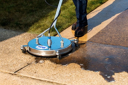 Surface cleaner being used to clean up concrete, showing dirty concrete next to clean concrete