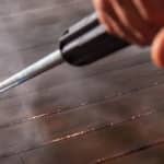 Up-close shot of power washing wand being used to wash floor of a wooden deck
