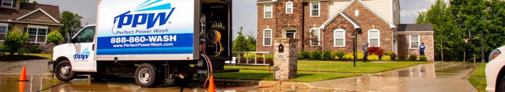 Perfect Power Wash truck in cul-de-sac in front of brick and vinyl home with two technicians working in the distance