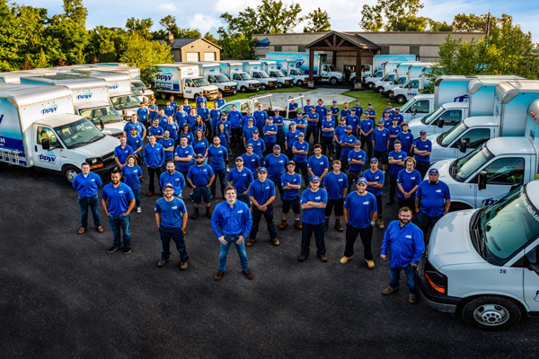 Perfect Power Wash team standing in front of building and fleet of power washing trucks