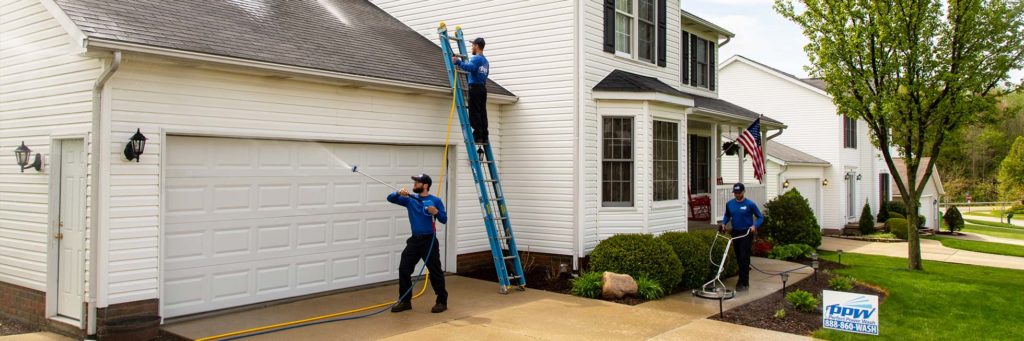 Professional power washing technicians working to improve curb appeal on a vinyl sided home.