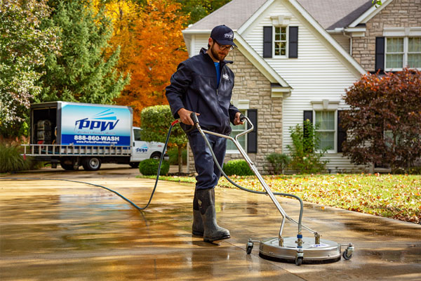 Image of a Perfect Power Wash technician cleaning concrete with a surface cleaner