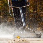 A surface cleaner is being used to power wash a concrete driveway