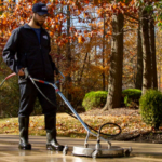 Perfect Power Wash technician surface cleaning a concrete driveway during the fall