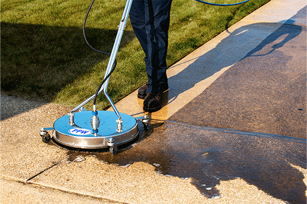 A surface cleaner power washes a concrete driveway