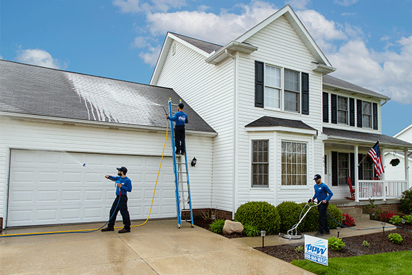 Perfect Power Wash technicians cleaning a roof, driveway, and house